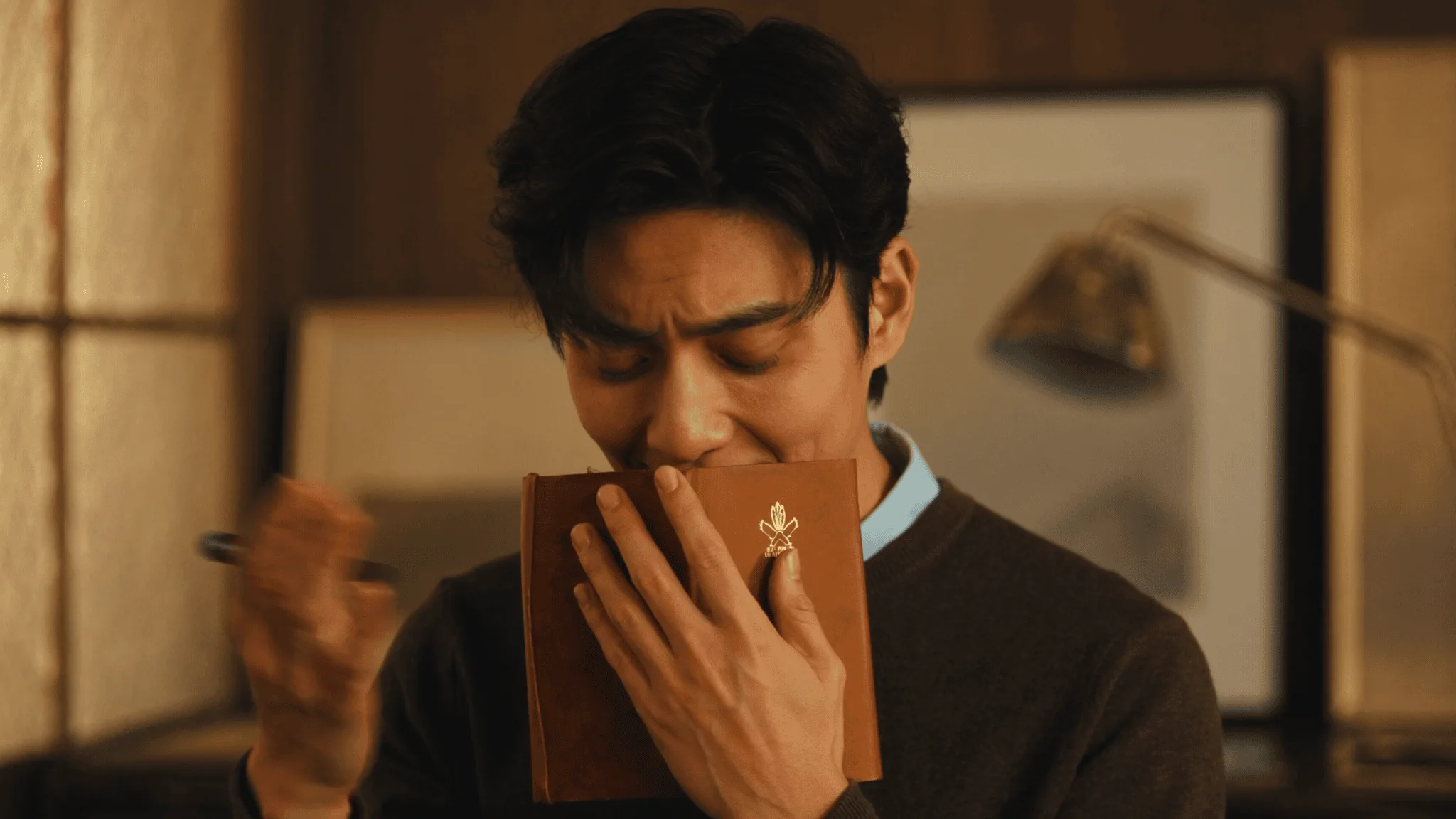 A young man holding his journal close with eyes closed in genuine emotional connection.